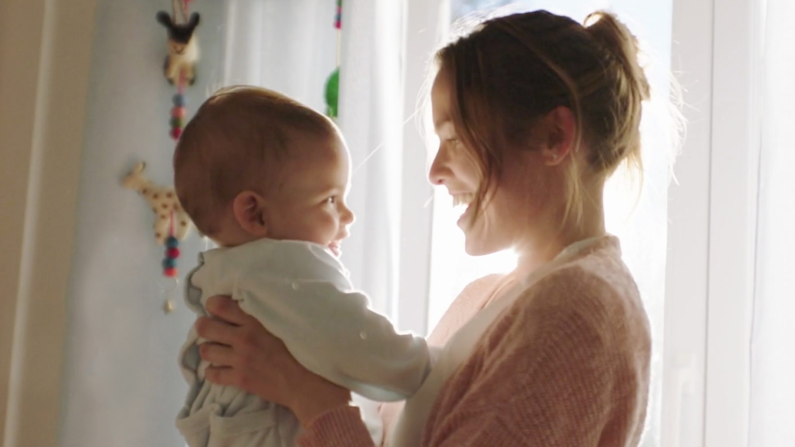 Fotografia de mãe e bebé num ambiente natural e luminoso, representando ternura e proximidade.
